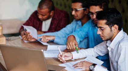 Group of four south asian men's posed at business meeting in cafe. Indians together and sign important documents. Contract to study and work.